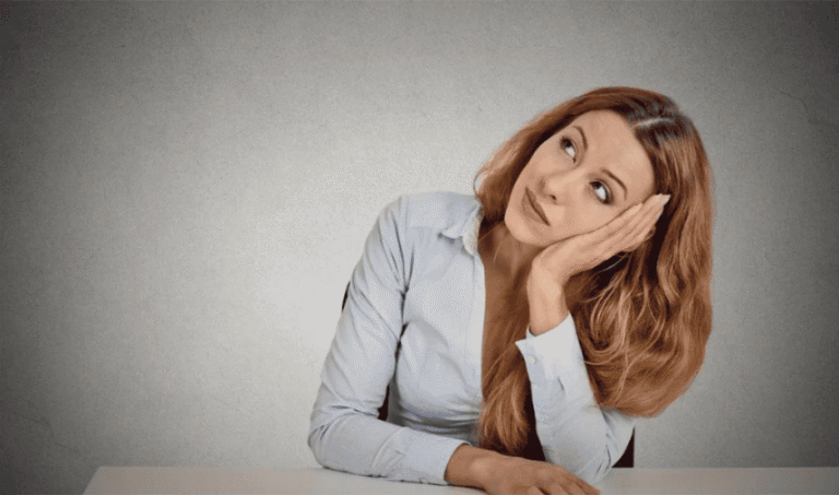 Woman resting her head on her hand and looking upward while thinking about TMS for OCD treatment options