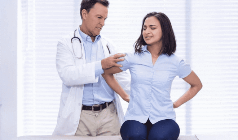 Doctor examining a woman holding her lower back in pain, a common reason for EMG testing for sciatica